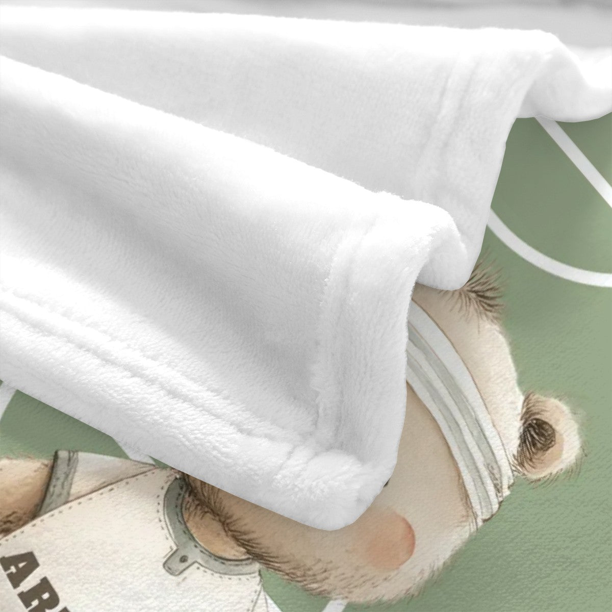 Close-up of soccer bear illustration on soft velvet nursery blanket.